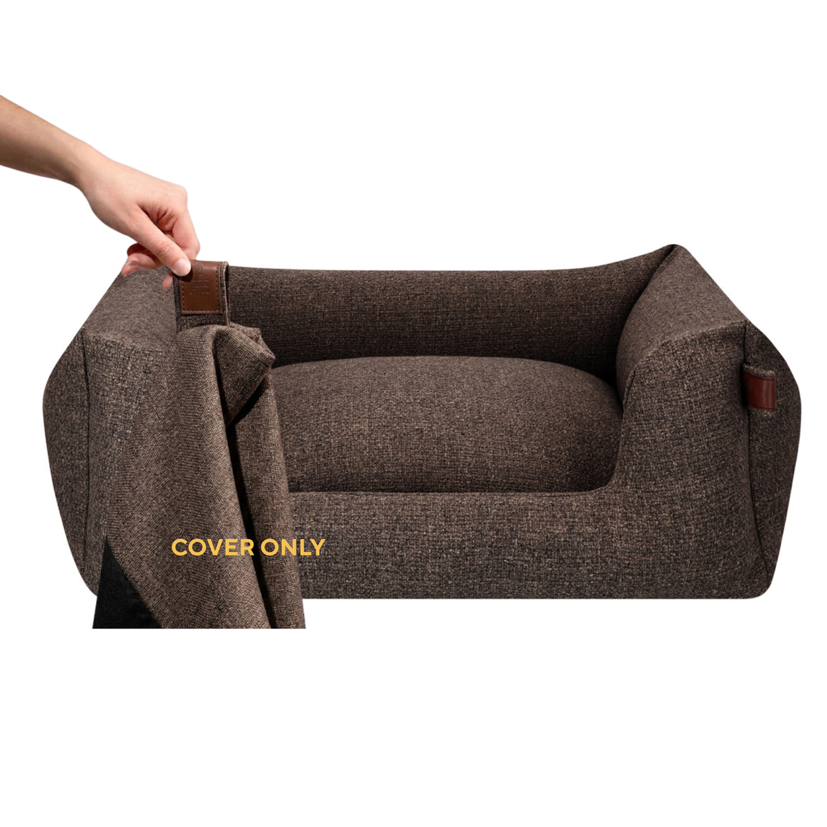 A brown textured pet bed with a matching fabric cover being held on by a hand, shown against a plain white background. The cover has a brown leather-like tab and the words 'COVER ONLY' are printed on it.