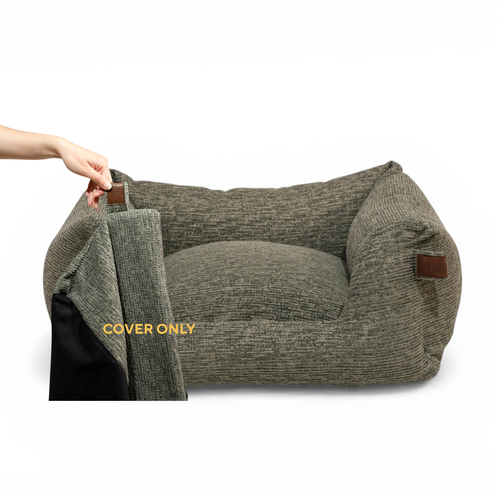 A textured green pet bed with a raised cushion and side bolsters, shown on a white background. A human hand is pulling away a matching gray cover on the left side, revealing a black interior.