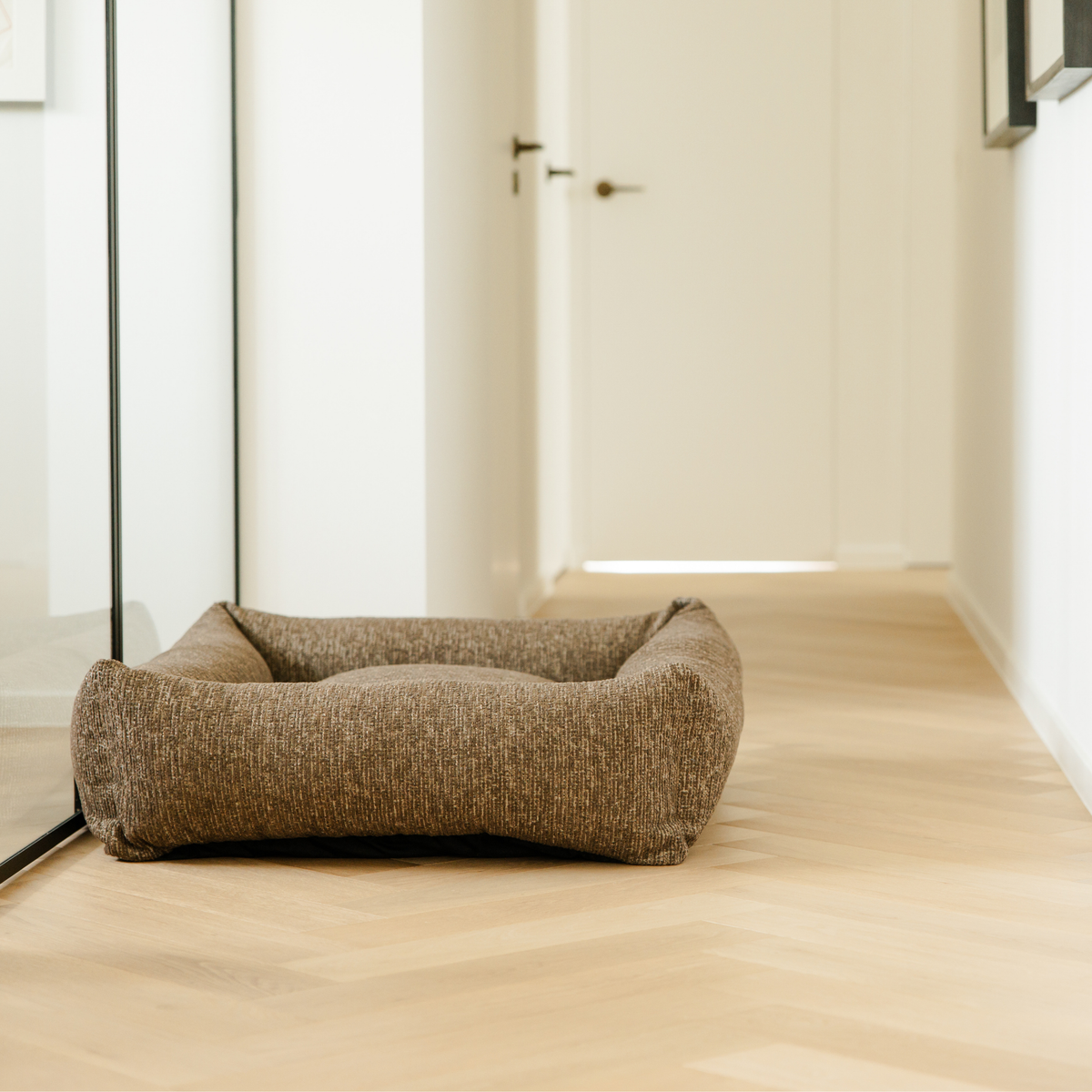 The Espresso Brown Snug dog bed on a herringbone floor in a light hallway