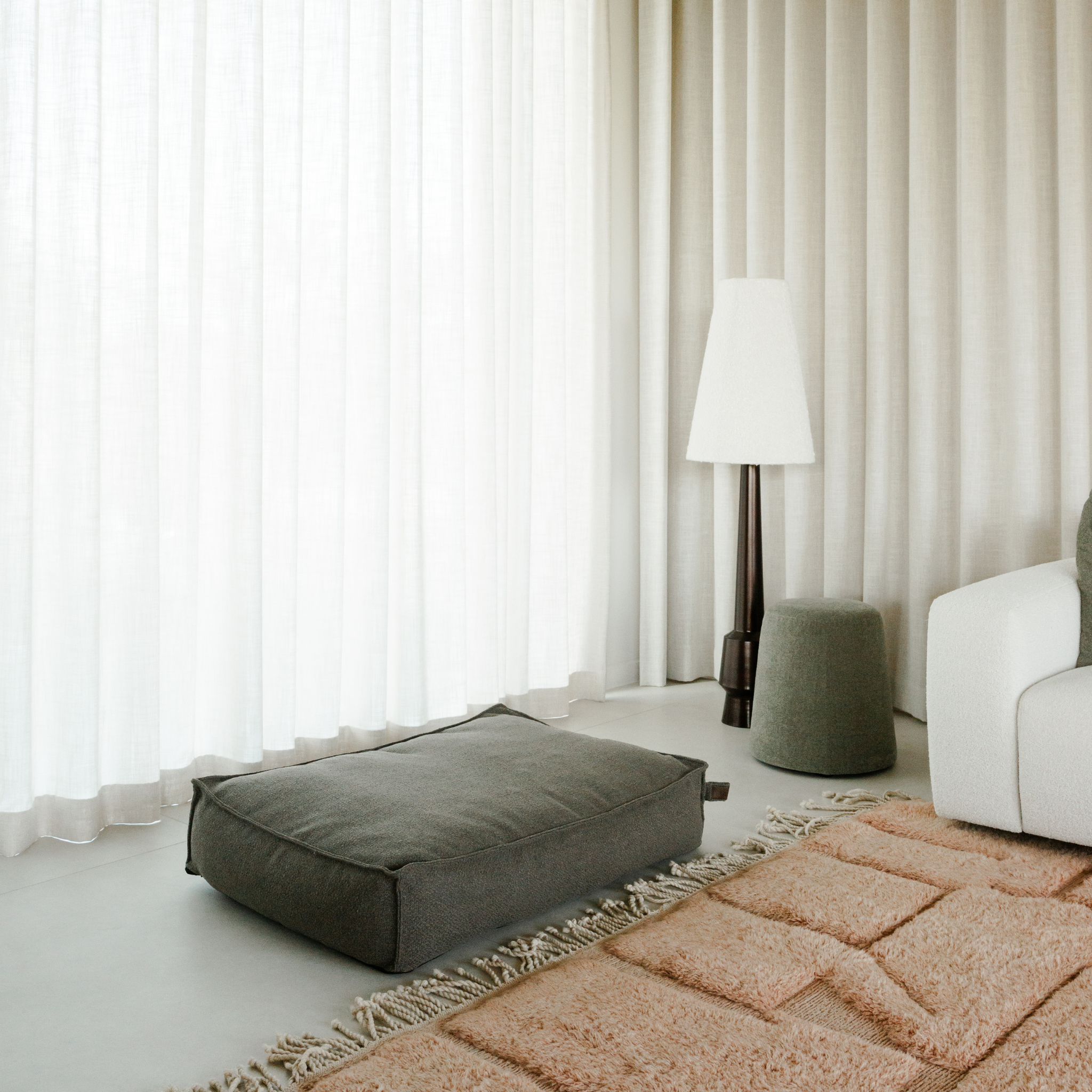 The Deep Taupe Stargaze dog mattress on a rug beside floor-length curtains