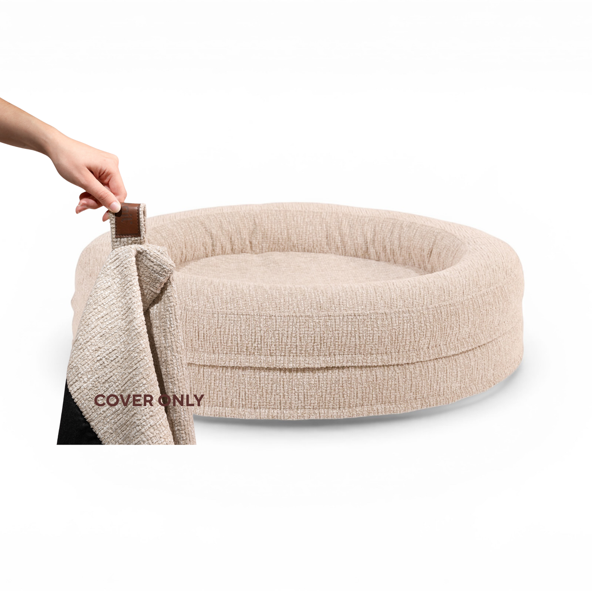A hand lifting the removable cover off the round Swirl dog bed in Clay Beige, labelled Cover only #color_clay-beige