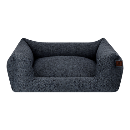 A darkblue textured pet bed with a raised cushioned wall and a small brown leather brand tag on the right side, shown against a plain white background.