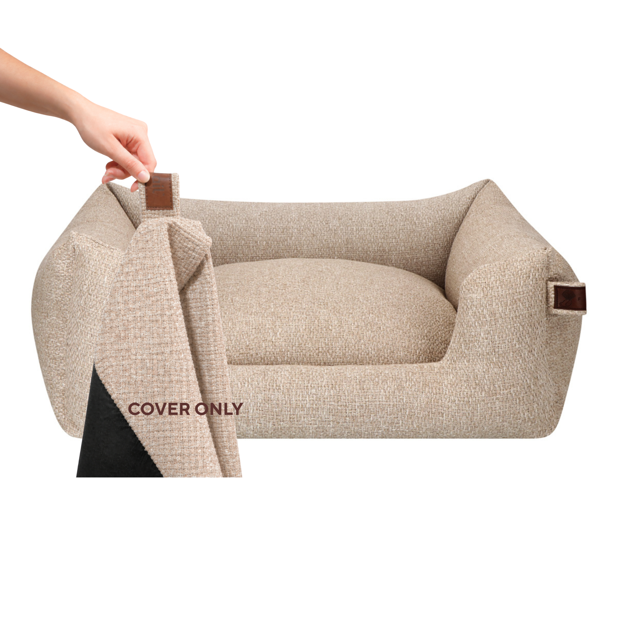 Beige textured pet bed cover shown on a raised pet bed, with a hand lifting the corner to reveal the black underside. A close-up inset at the bottom left shows the fabric texture and a brown tab detail.