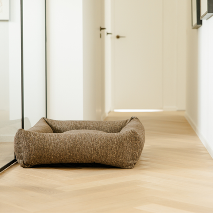 The Espresso Brown Snug dog bed on a herringbone floor in a light hallway 
