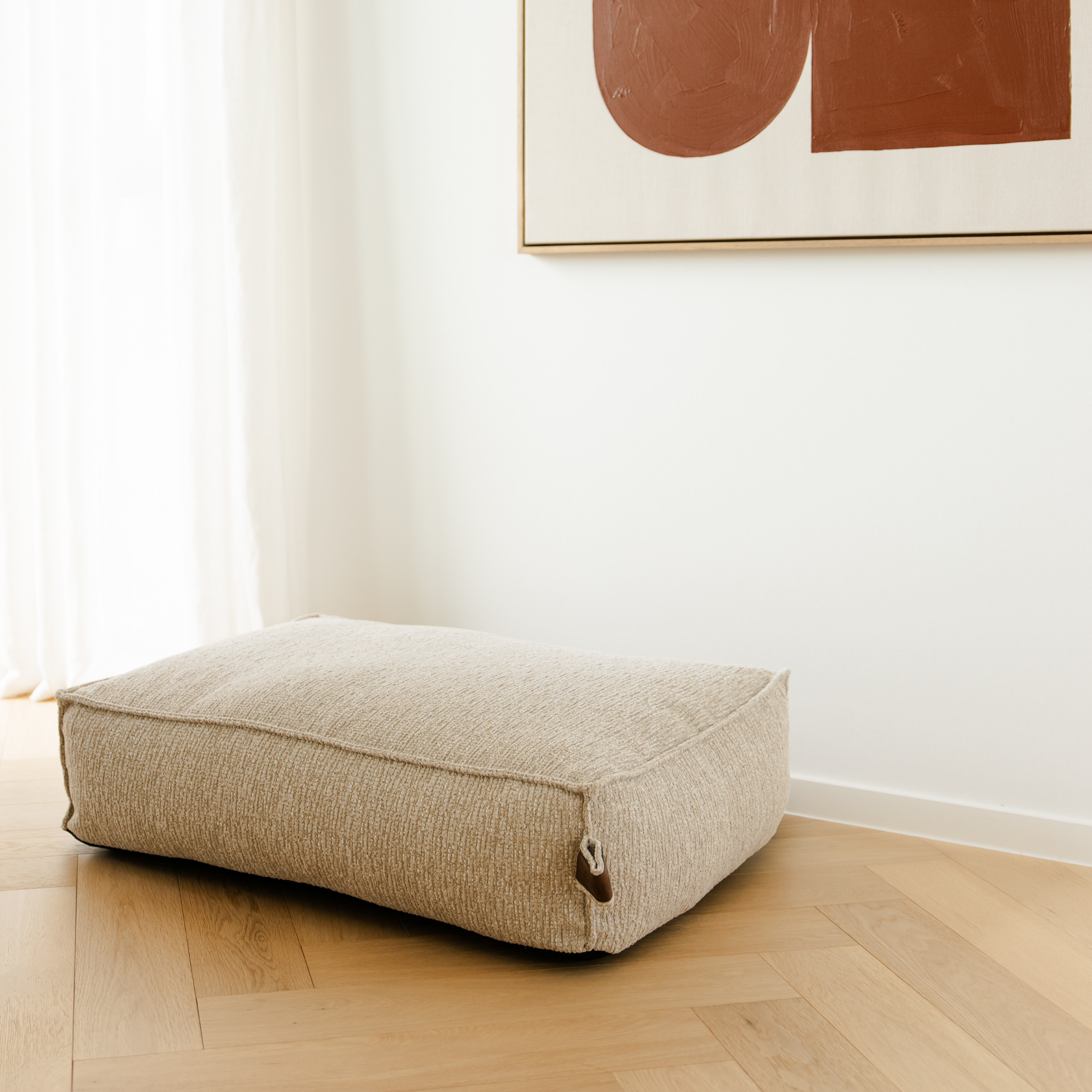 The Clay Beige Stargaze dog mattress in a bright room with a herringbone floor 