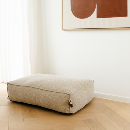 The Clay Beige Stargaze dog mattress in a bright room with a herringbone floor 